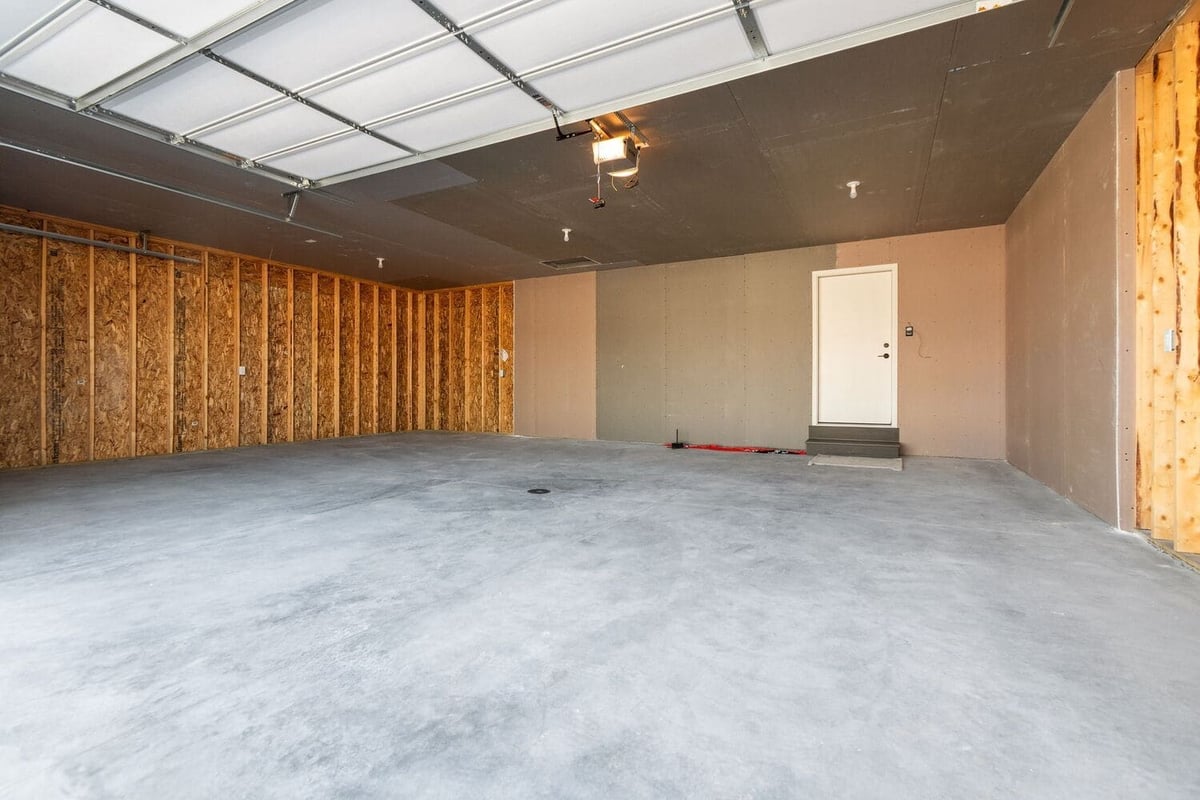 Unfinished two car garage with concrete floor, drywall, and overhead door, located in the Fox Cities