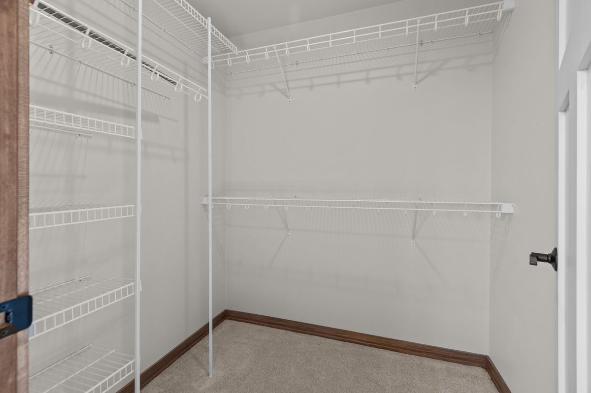 Walk-in closet with white wire shelving and carpeted floor in a new home, located in the Fox Cities