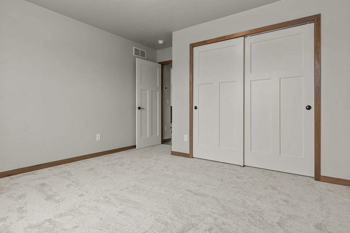 Custom bedroom with double closet doors and neutral tones by Midwest Design Homes in Neenah, WI