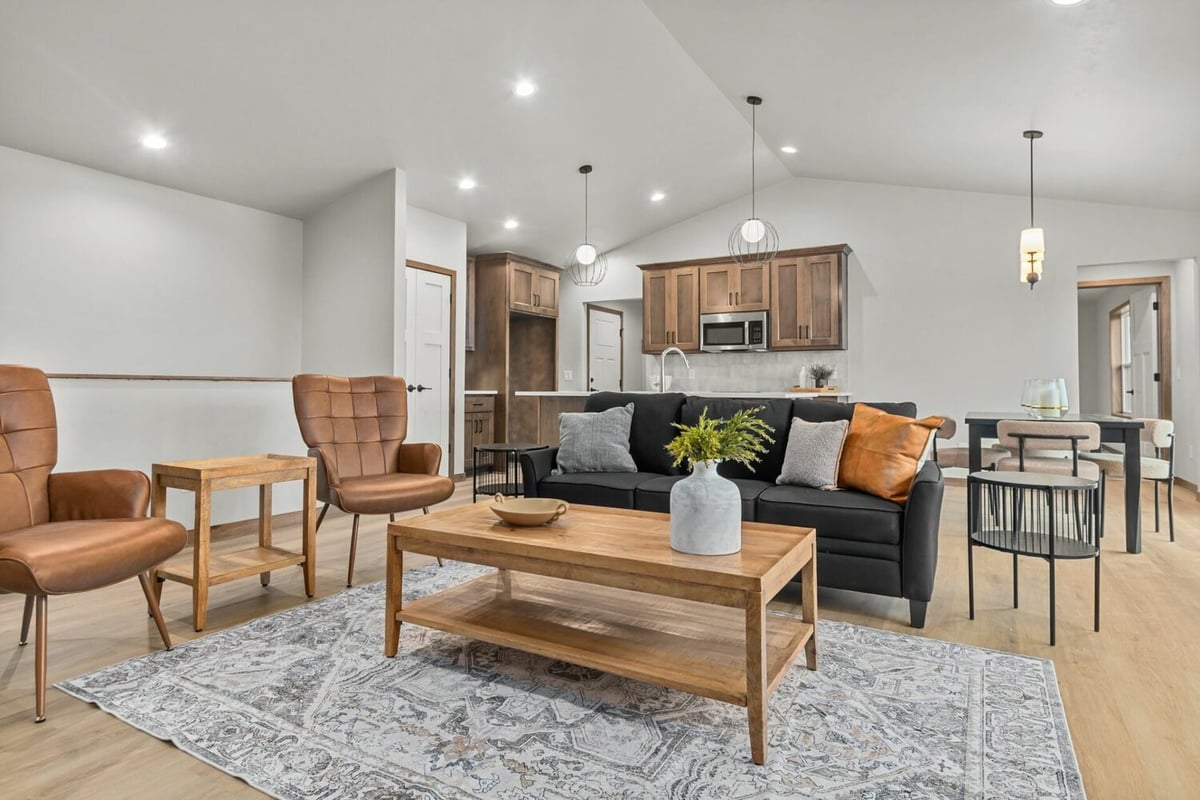 Custom living room and kitchen area with black sofa and pendant lighting by Midwest Design Homes in Harrison, WI