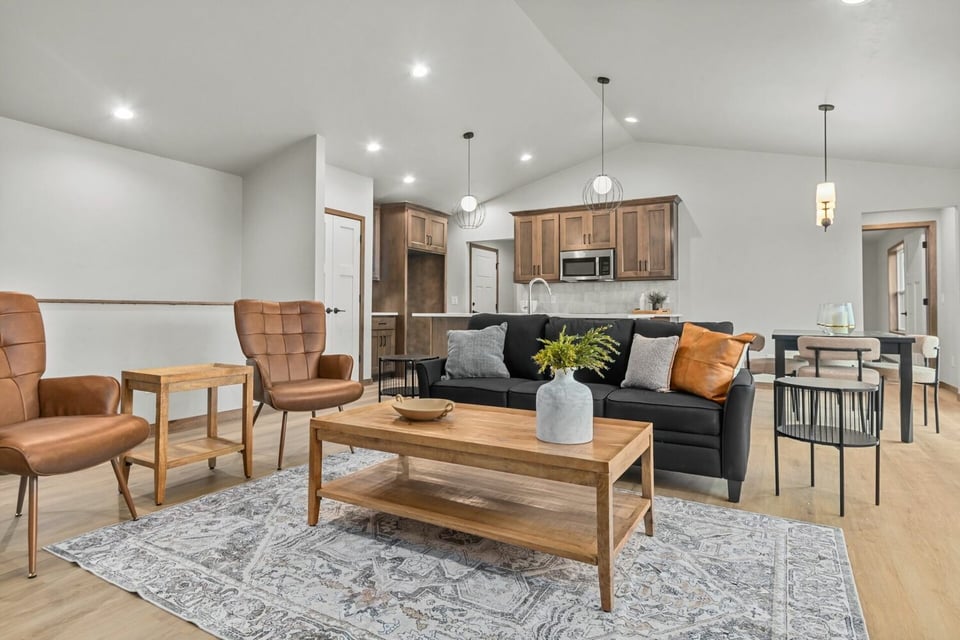 Custom living room and kitchen area with black sofa and pendant lighting by Midwest Design Homes in Harrison, WI