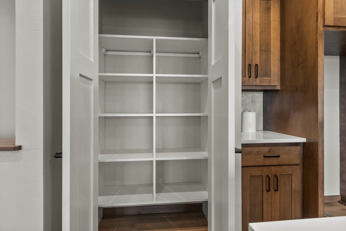Dual-door pantry with built-in shelving in a custom kitchen by Midwest Design Homes in Ledgeview, WI.