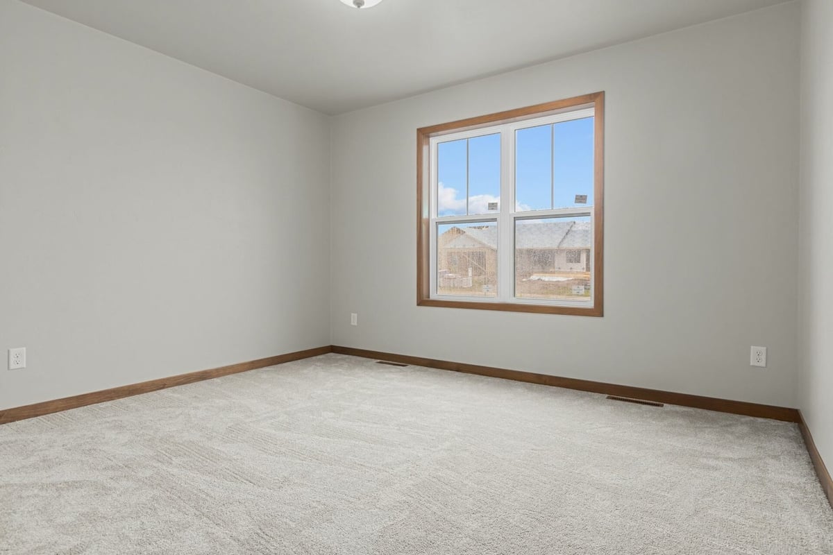 Empty bedroom with natural light and soft carpeting by Midwest Design Homes in Lawrence, WI