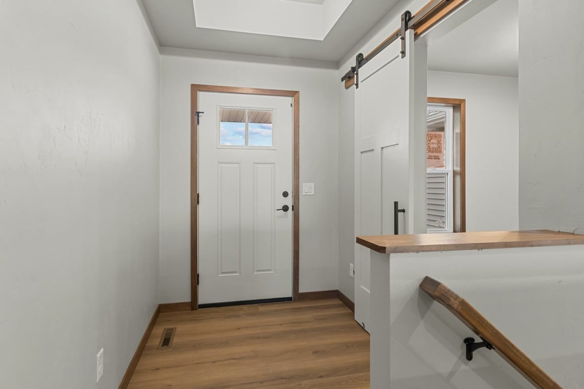 Entryway with white door and barn-style sliding door in custom home by Midwest Design Homes in Harrison, WI