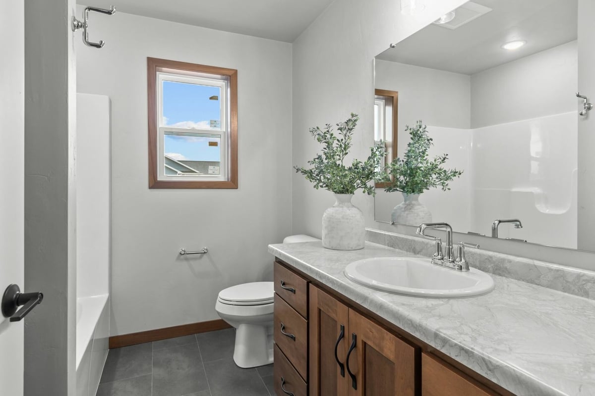Guest bathroom with wood vanity and white countertop in a custom home by Midwest Design Homes in Bellevue, WI