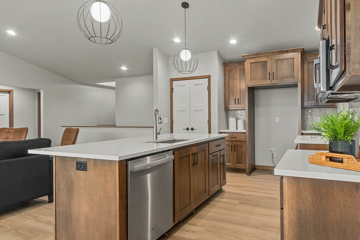 Kitchen island with stainless steel dishwasher and wood cabinetry in a Midwest Design Homes custom home in Ellington, WI