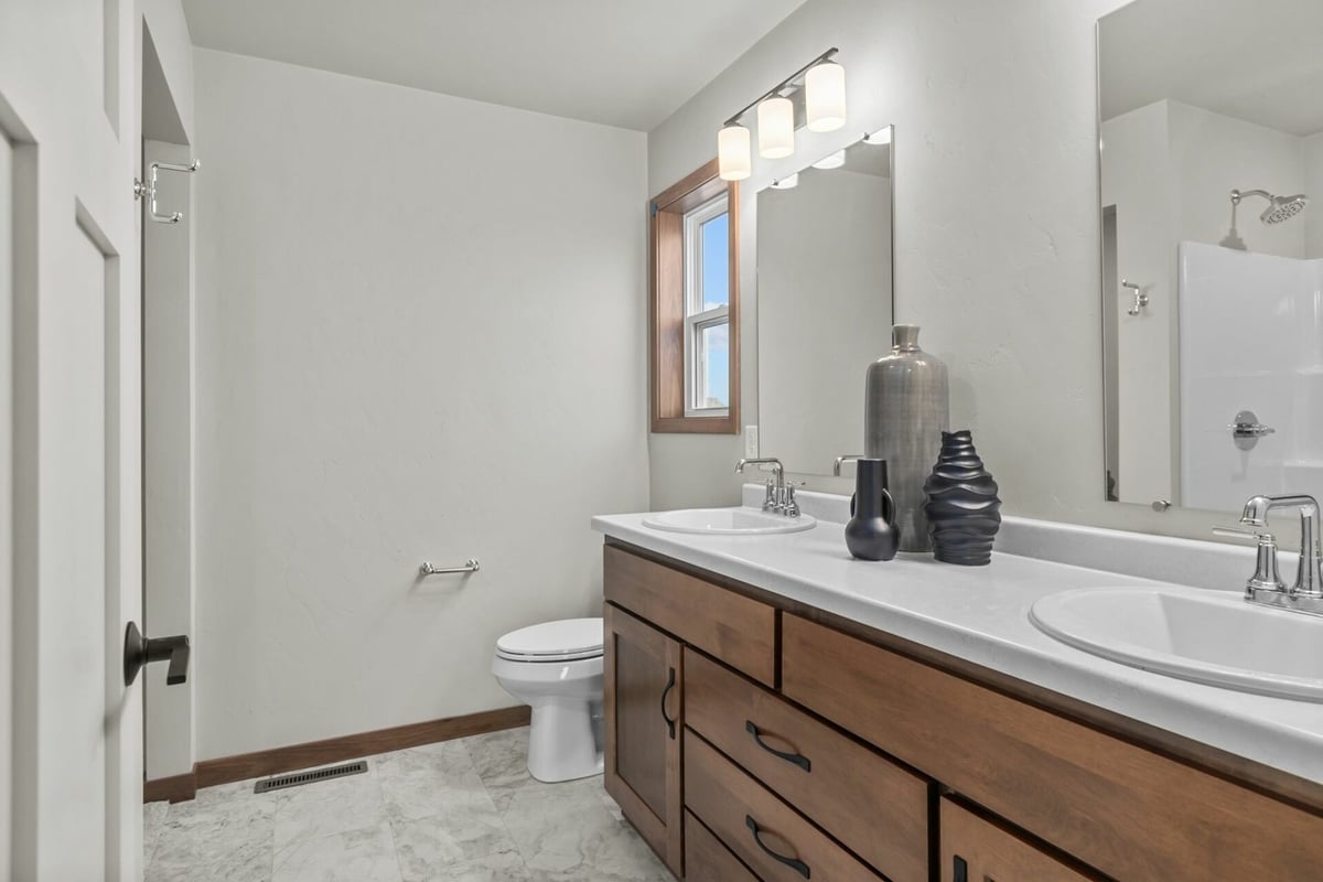 Modern bathroom with double vanity and wood cabinetry in a Midwest Design Homes custom home in Kaukauna, WI