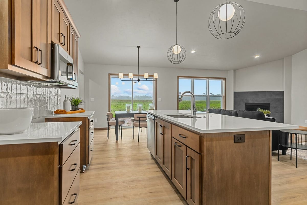 Open concept kitchen and dining area with island and pendant lights by Midwest Design Homes in Harrison, WI