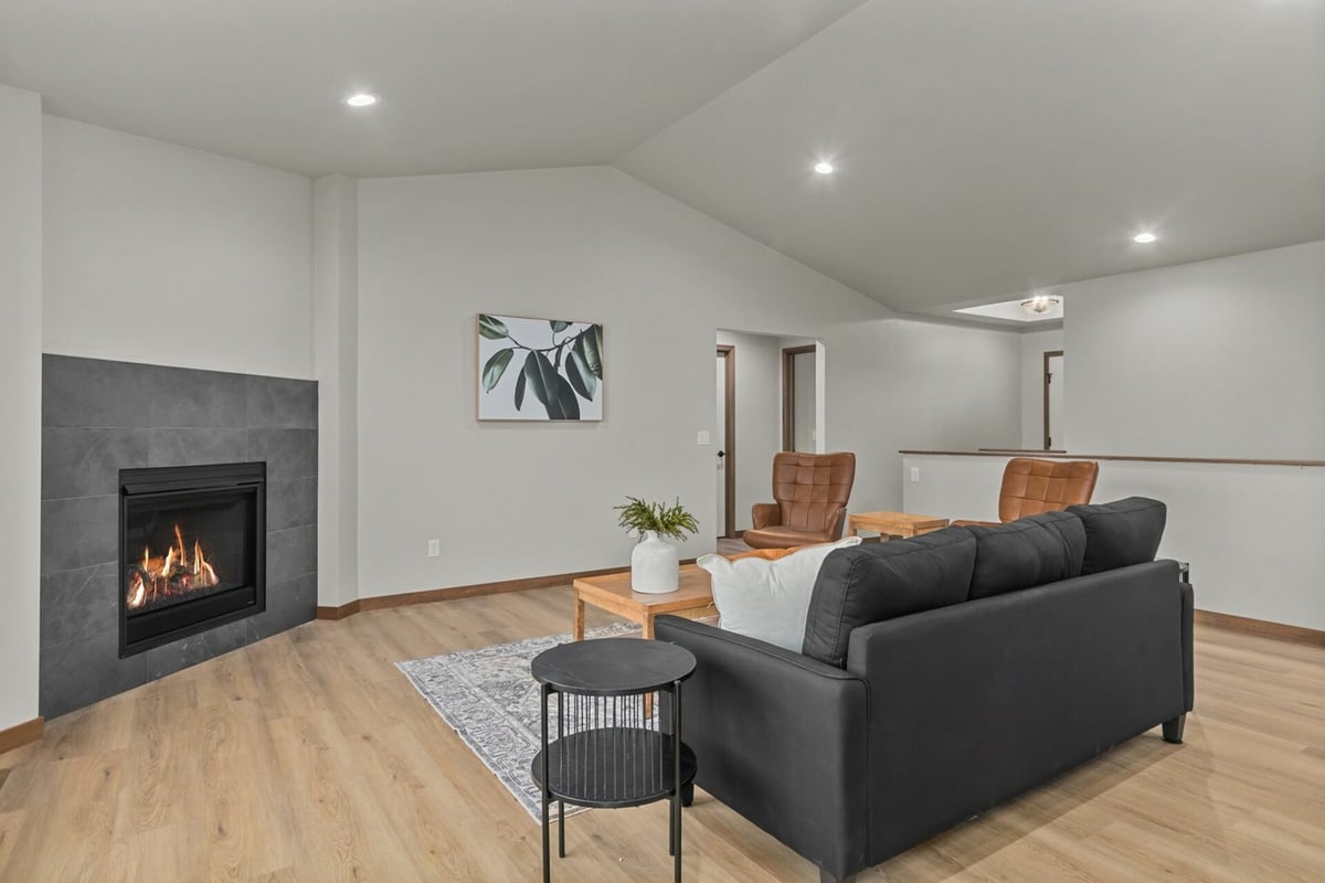 Open concept living room with fireplace and leather chairs by Midwest Design Homes in Ledgeview, WI