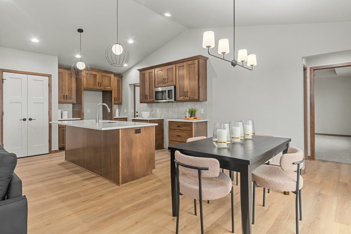 Open-concept kitchen and dining area with natural wood cabinetry in a custom home by Midwest Design Homes in De Pere, WI