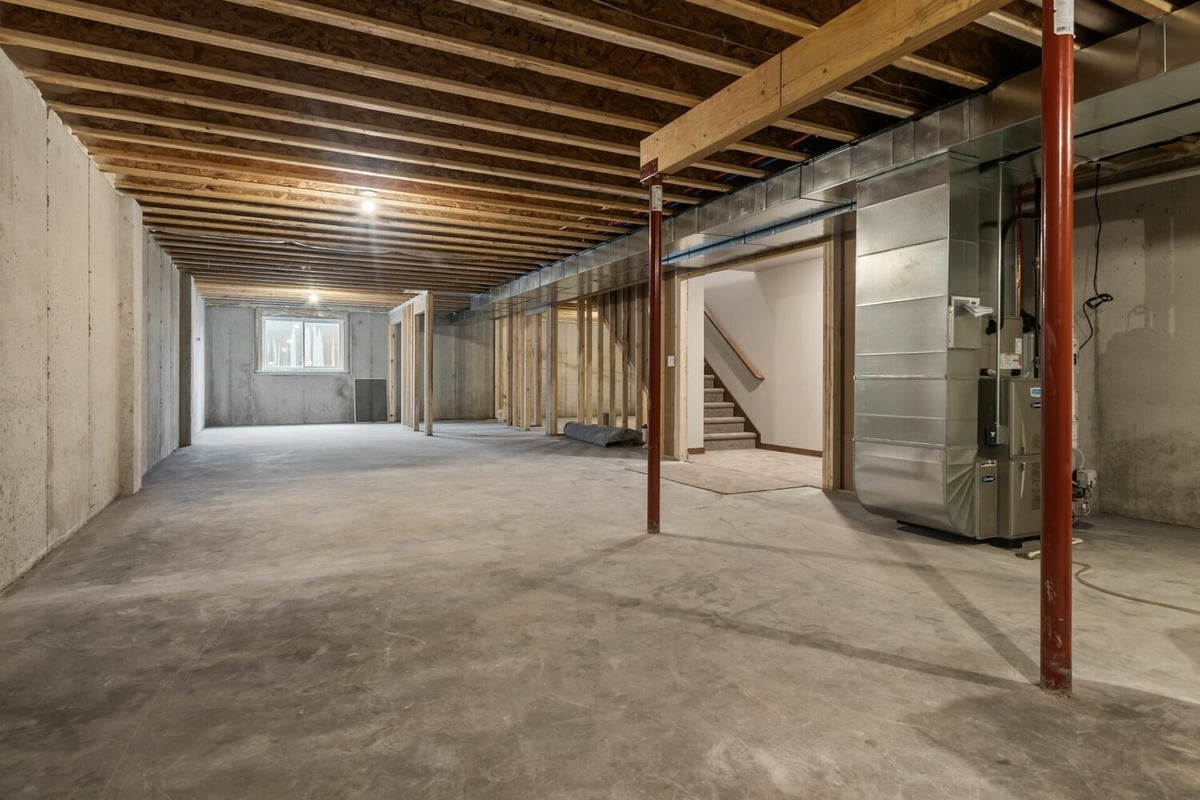 Spacious unfinished basement with exposed beams in custom home by Midwest Design Homes in Kaukauna, WI