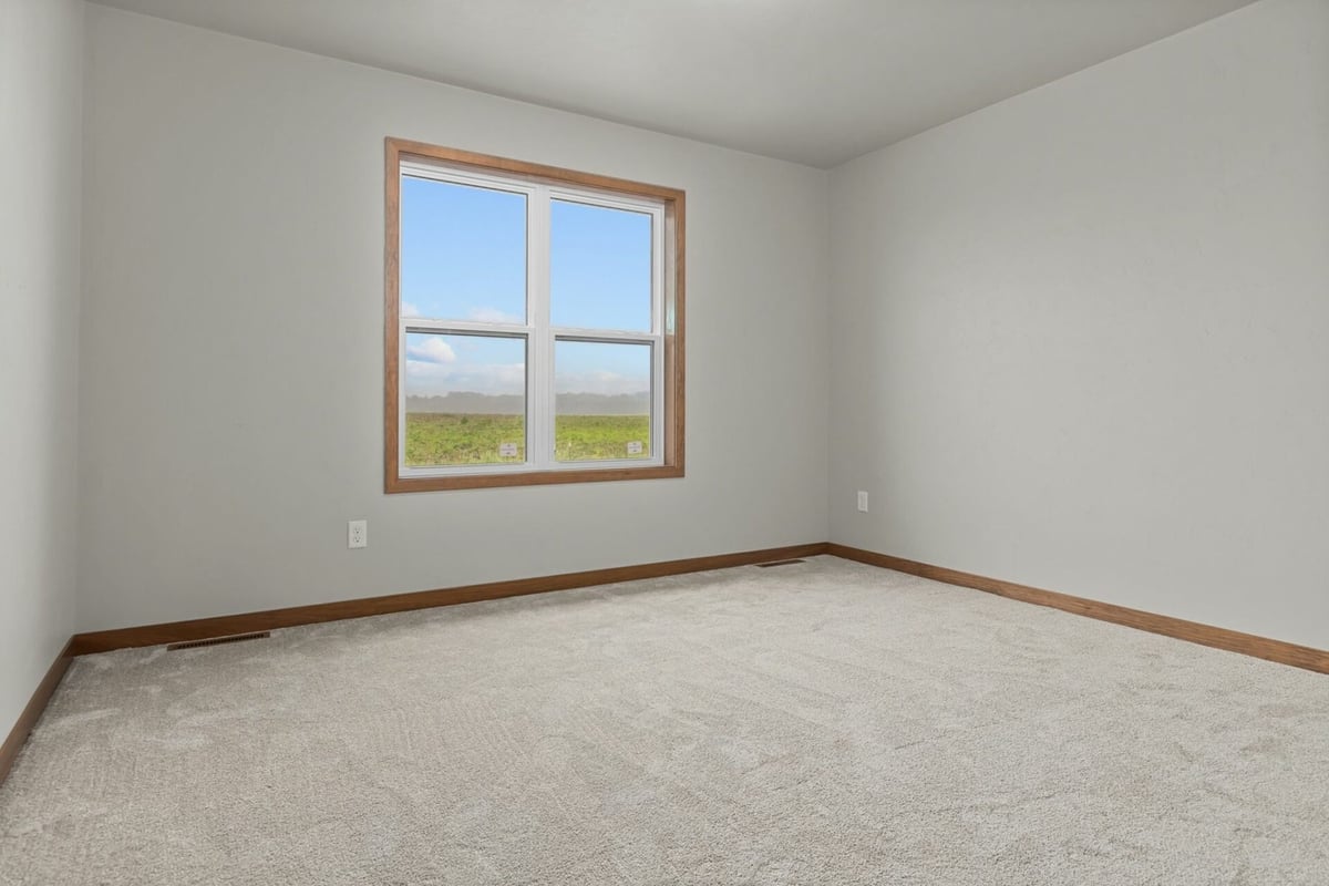 Unfurnished bedroom with plush carpet and large window by Midwest Design Homes in Appleton, WI