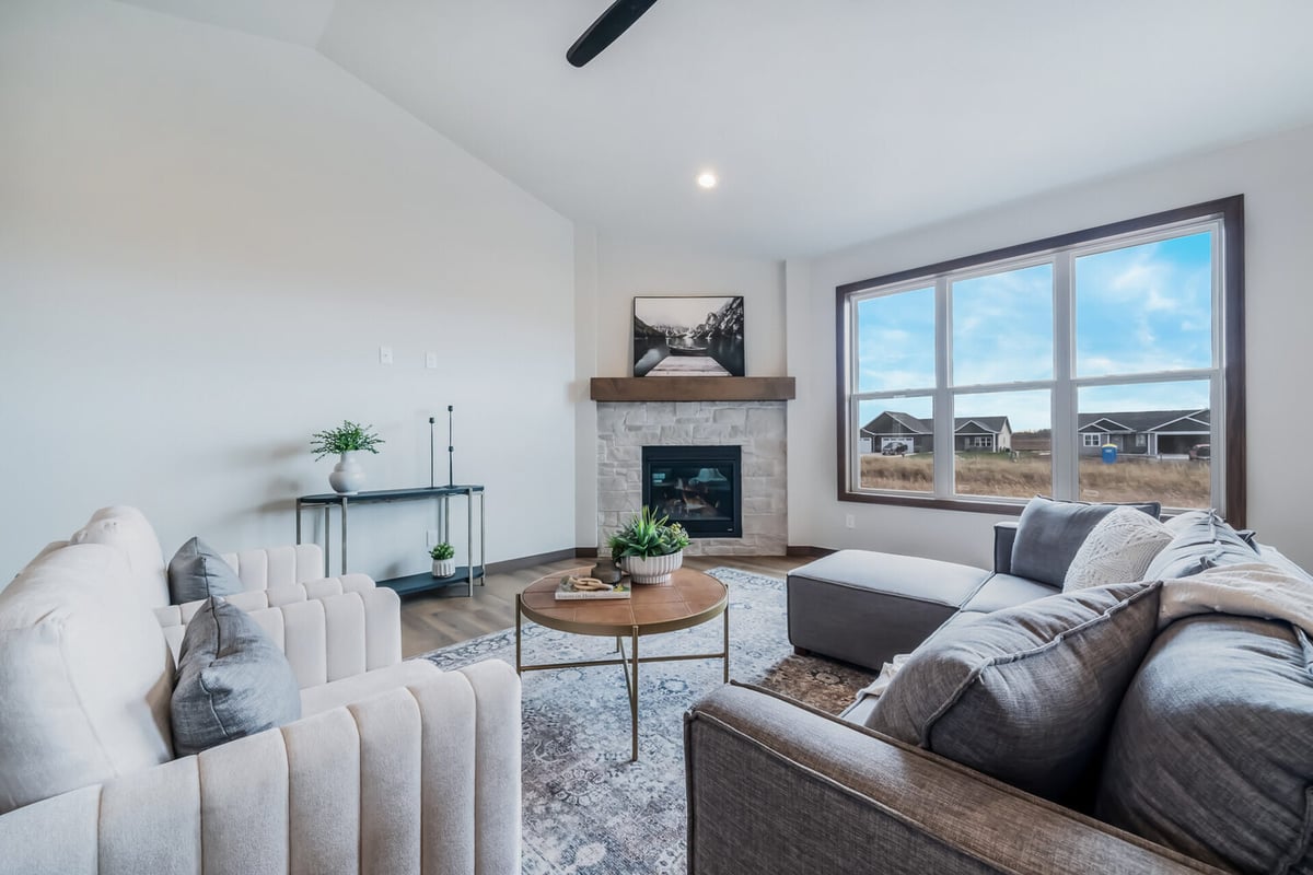 Cozy living room with stone fireplace and large windows in a custom Midwest Design Homes project in Kaukauna, WI