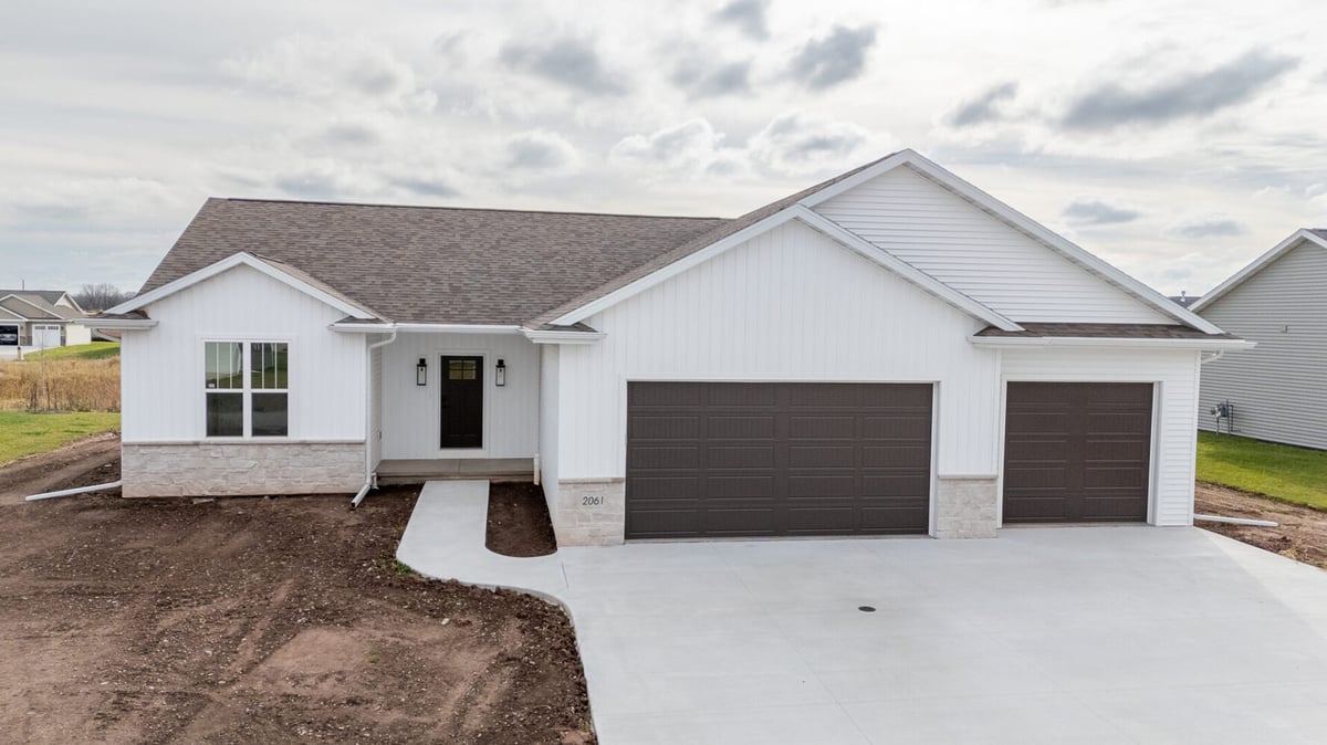 Front angle of custom-built home featuring white siding and dark garage doors by Midwest Design Homes in Fox Cities, WI