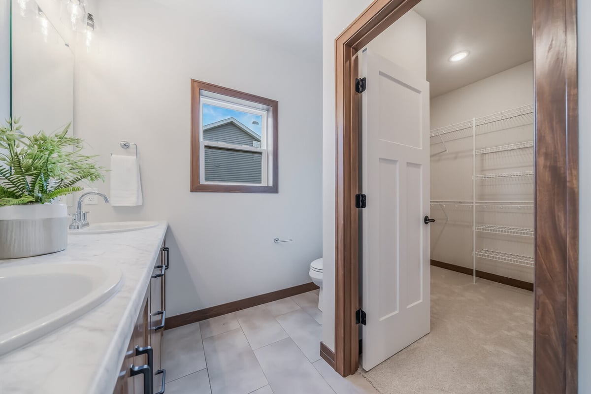 Master bathroom vanity area with dual sinks and view into walk-in closet by Midwest Design Homes in Lawrence, WI.
