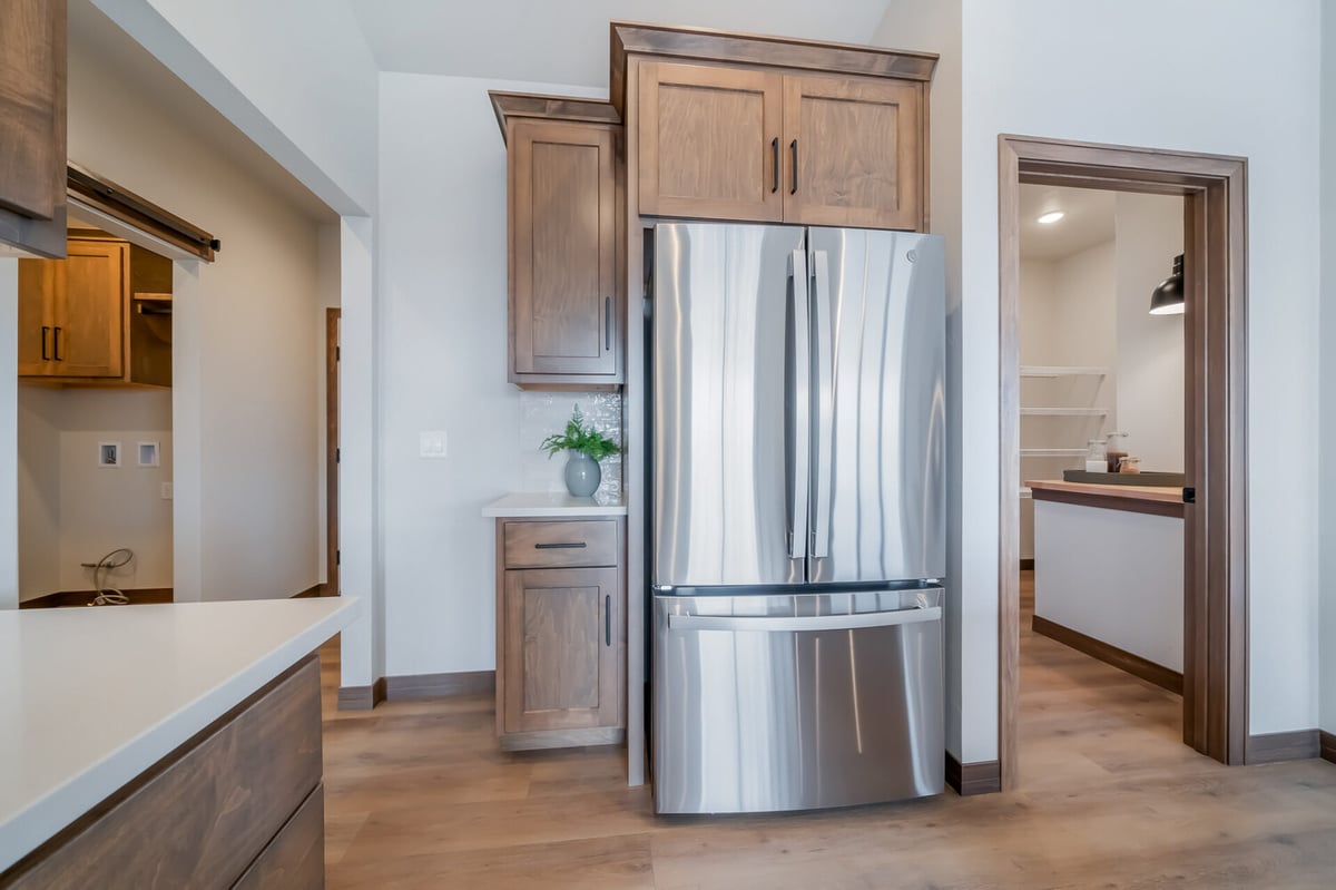 Refrigerator wall with adjacent pantry and laundry access in a Midwest Design Homes custom home in Kaukauna, WI