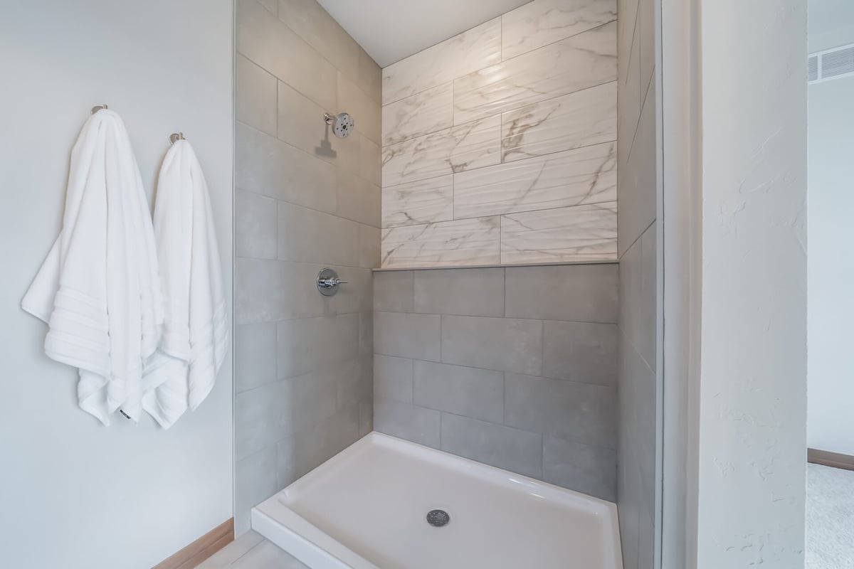 Tiled walk-in shower with marble accent wall in custom Midwest Design Homes project in Appleton, WI