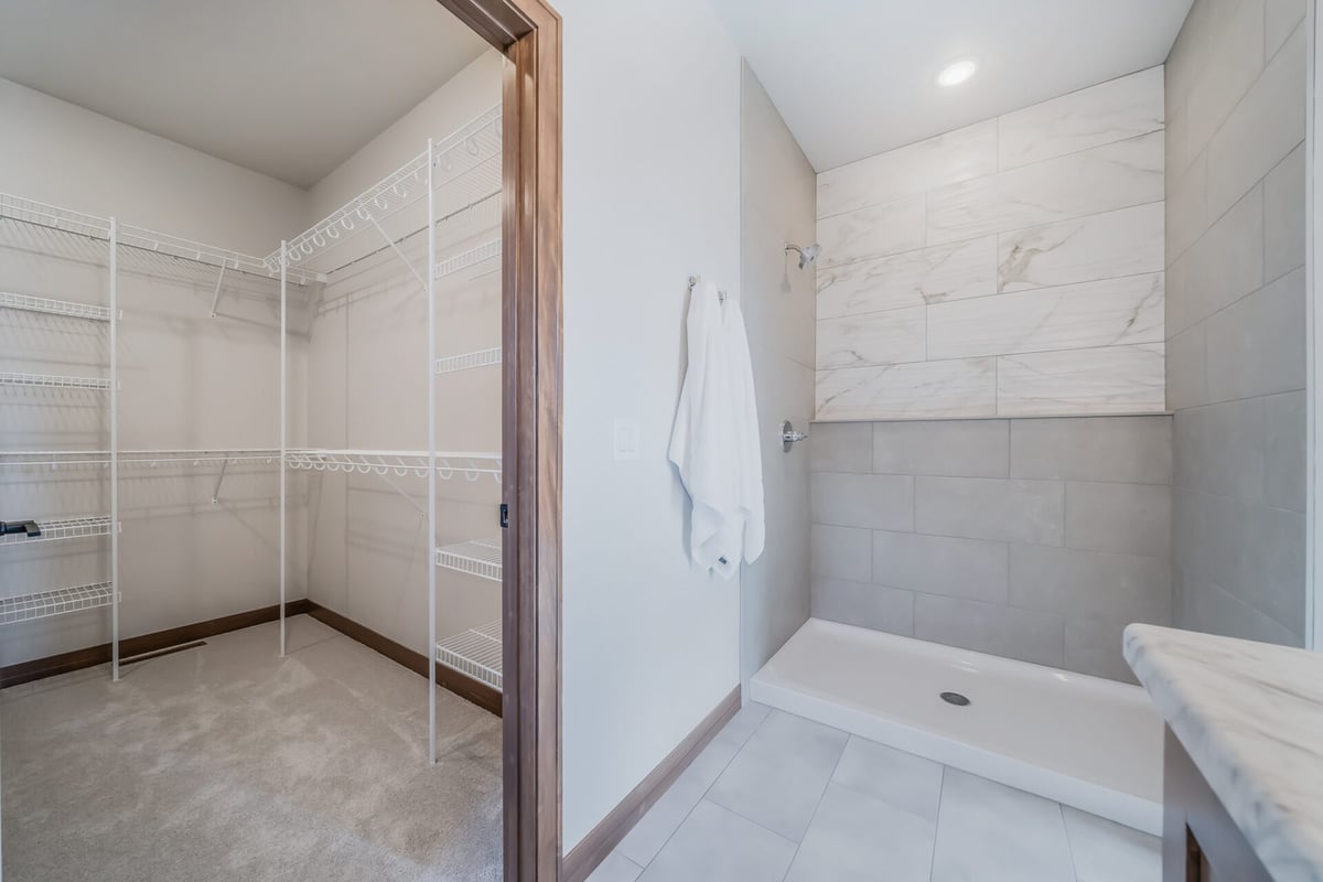 Walk-in closet and tile shower combination in primary suite by Midwest Design Homes in Neenah, WI