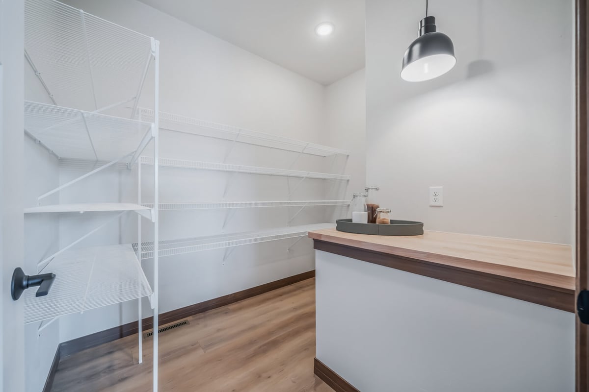 Walk-in pantry with white shelving and wood countertop in a custom Kaukauna, WI home by Midwest Design Homes