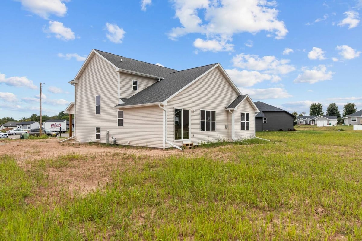 Backyard view of two-story home with sliding doors in a De Pere, WI build by Midwest Design Homes