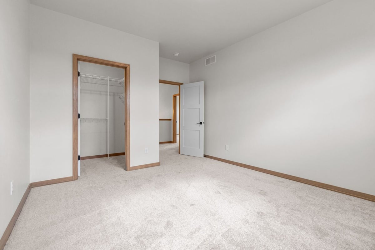 Bedroom with walk-in closet and neutral color palette in a custom home by Midwest Design Homes in Fox Cities, WI