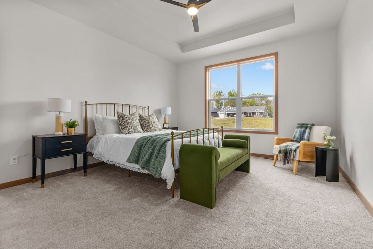 Bright primary bedroom with gold bed frame and green bench in a Midwest Design Homes custom home in Appleton, WI