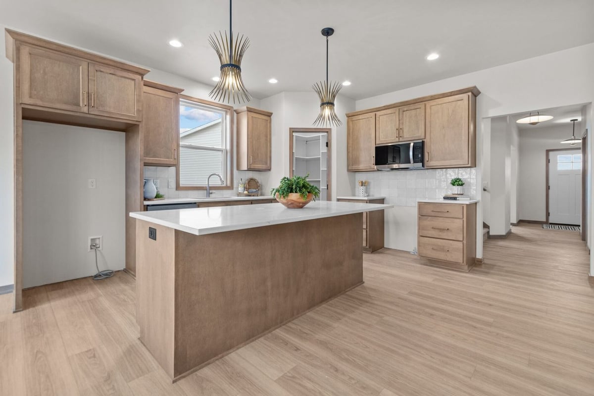 Custom kitchen with quartz island, pendant lighting, and open pantry by Midwest Design Homes in Kaukauna, WI
