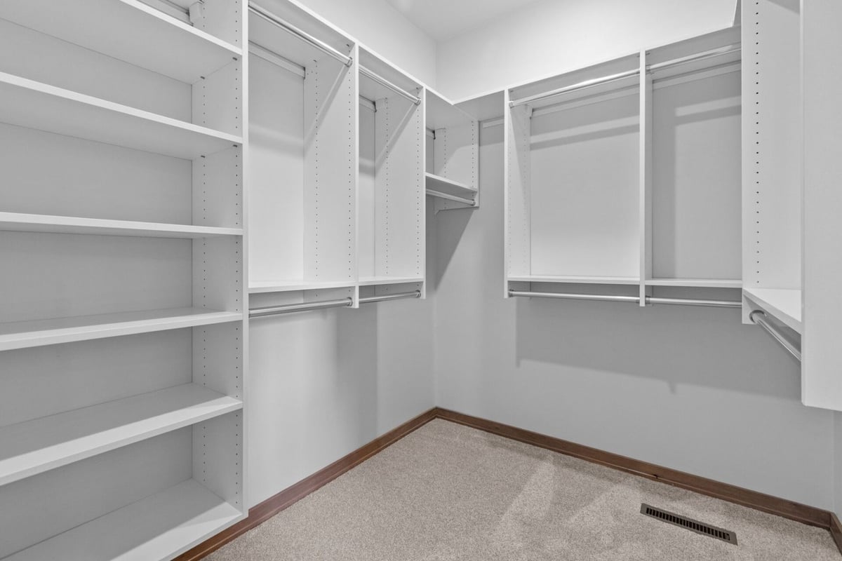 Custom walk-in closet with white built-in shelving by Midwest Design Homes in Kaukauna, Wisconsin