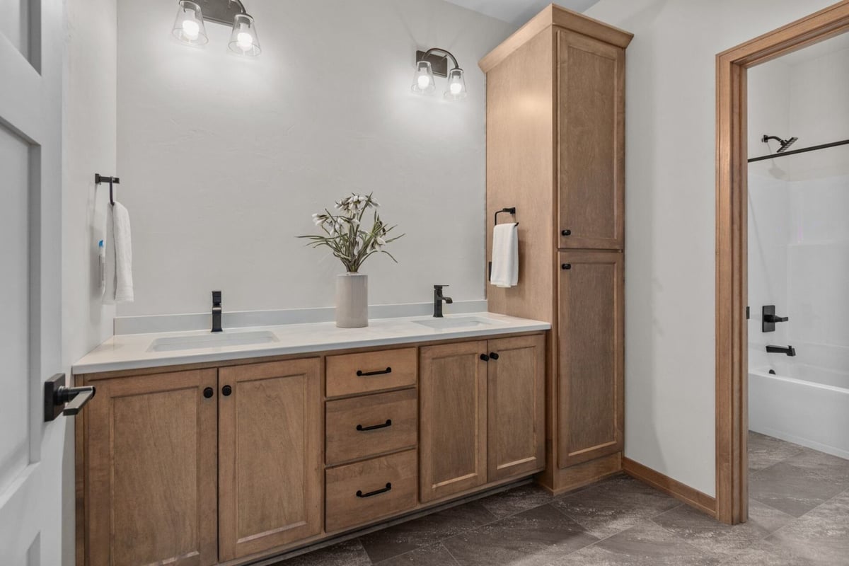 Double-sink vanity with wood cabinetry in a Midwest Design Homes bathroom in Ellington, WI