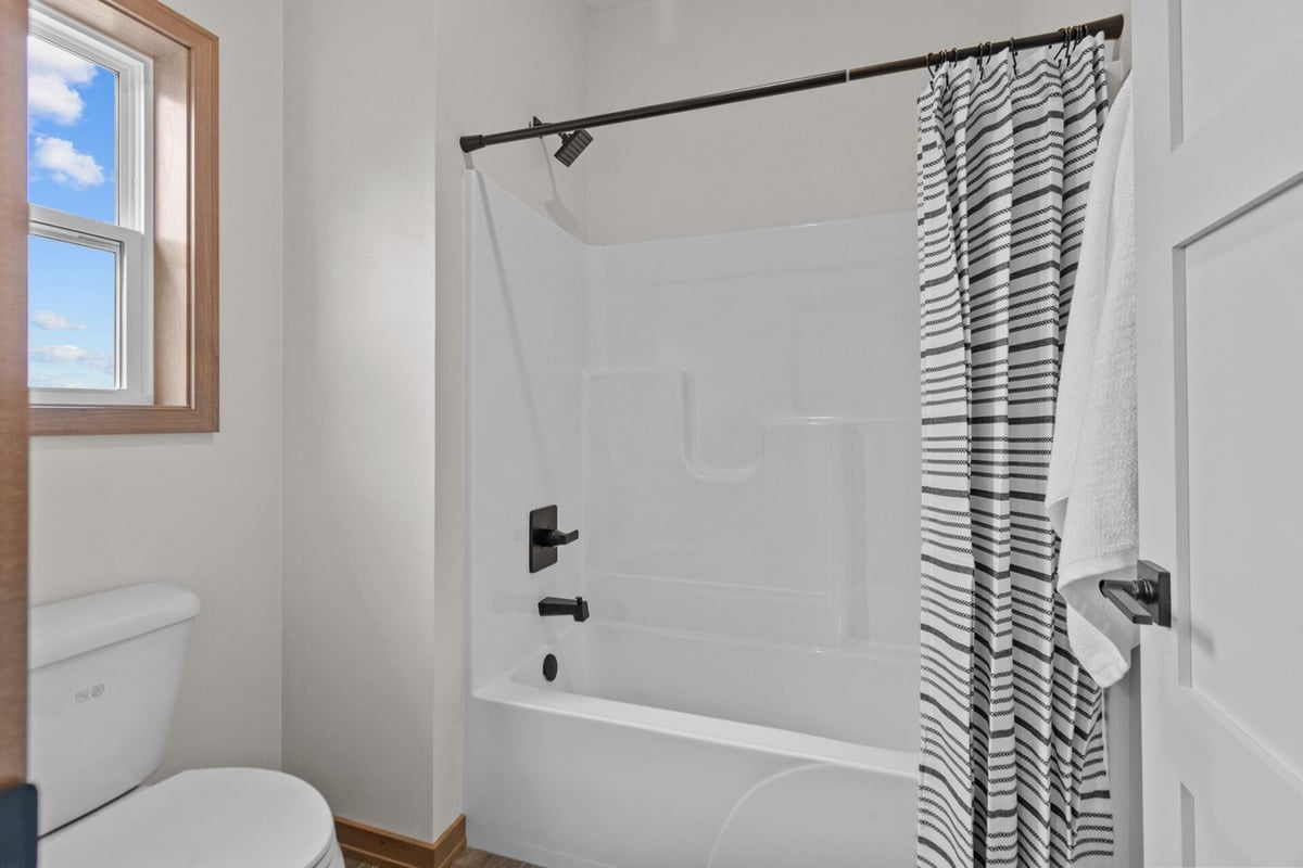Full bathroom with shower-tub combo and matte black fixtures in a Midwest Design Homes custom build in Kaukauna, WI