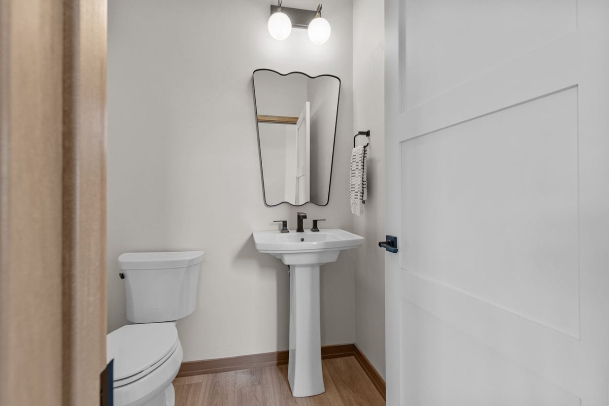 Half bathroom with pedestal sink and modern mirror in a Midwest Design Homes custom home in Kaukauna, WI