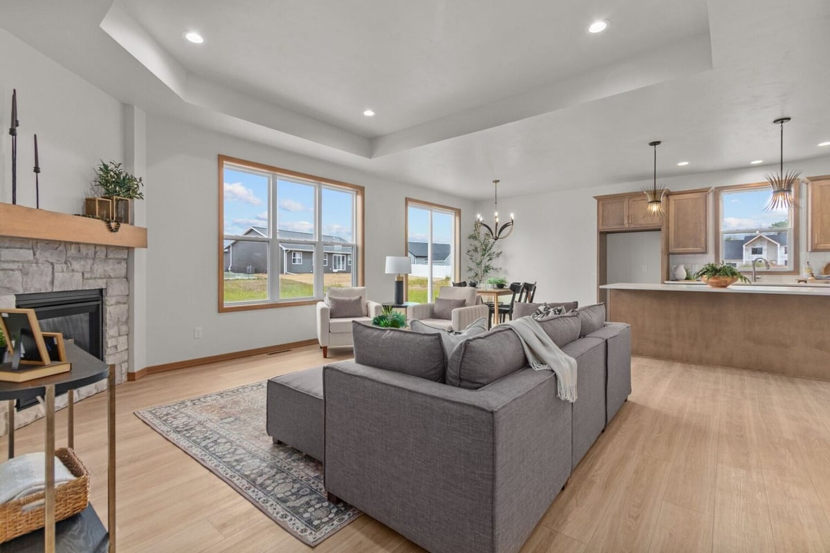 Living area with fireplace and view into modern kitchen in a Kaukauna, WI custom home by Midwest Design Homes