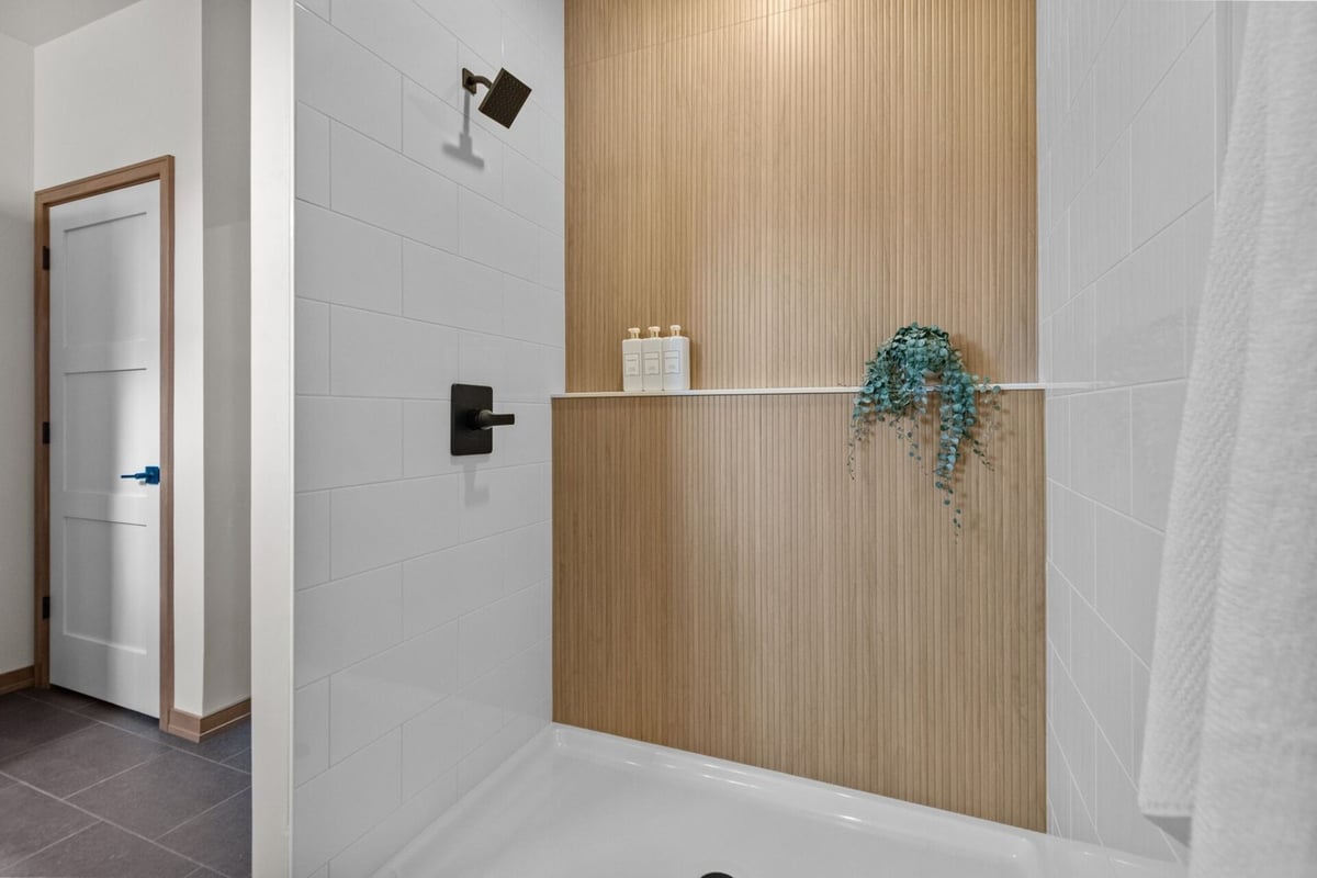 Modern shower design with vertical wood-look tile accent in a Midwest Design Homes custom home in Appleton, WI