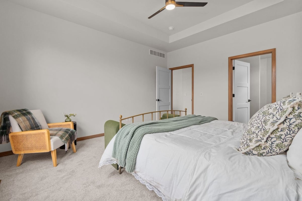 Primary bedroom corner with accent chair and cozy throw in a Green Bay, WI custom home by Midwest Design Homes