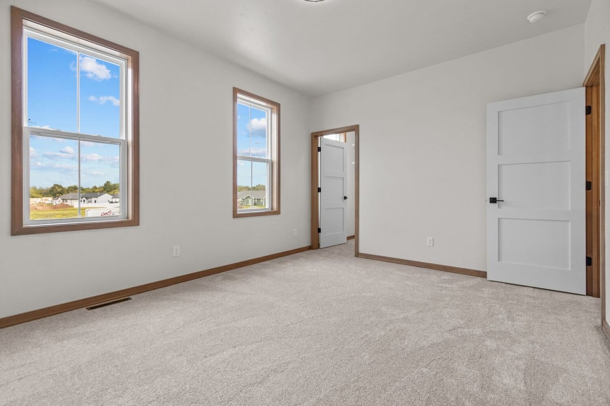 Simple bedroom with modern trim and two large windows in a Green Bay, WI custom home by Midwest Design Homes
