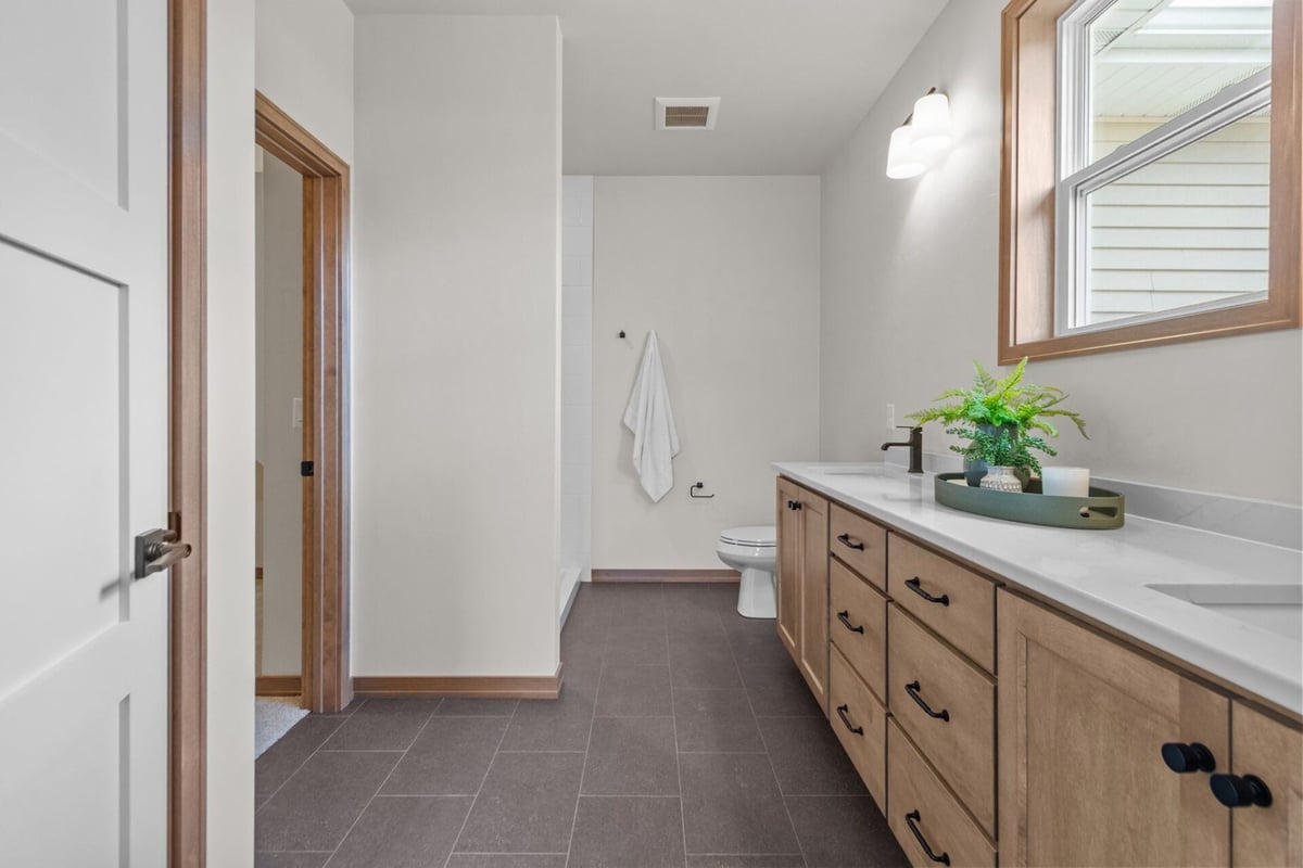 Spacious bathroom design with wood cabinets and black hardware in a Fremont, WI home by Midwest Design Homes