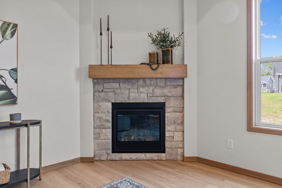 Stone fireplace with wood mantle in a Midwest Design Homes living room in De Pere, WI