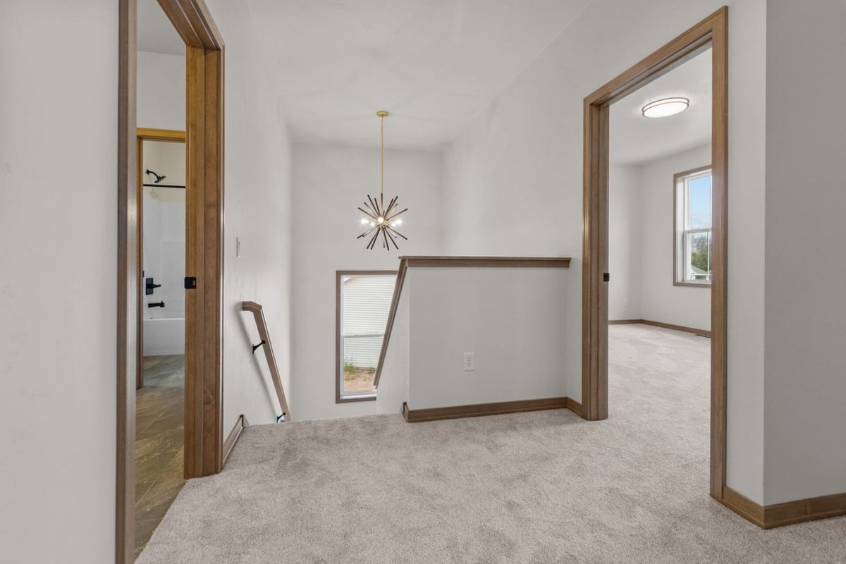 Upper-level hallway with modern chandelier in a custom home by Midwest Design Homes in Neenah, WI