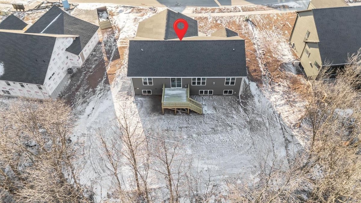 Aerial rear view of Fox Cities home with deck and wooded backdrop