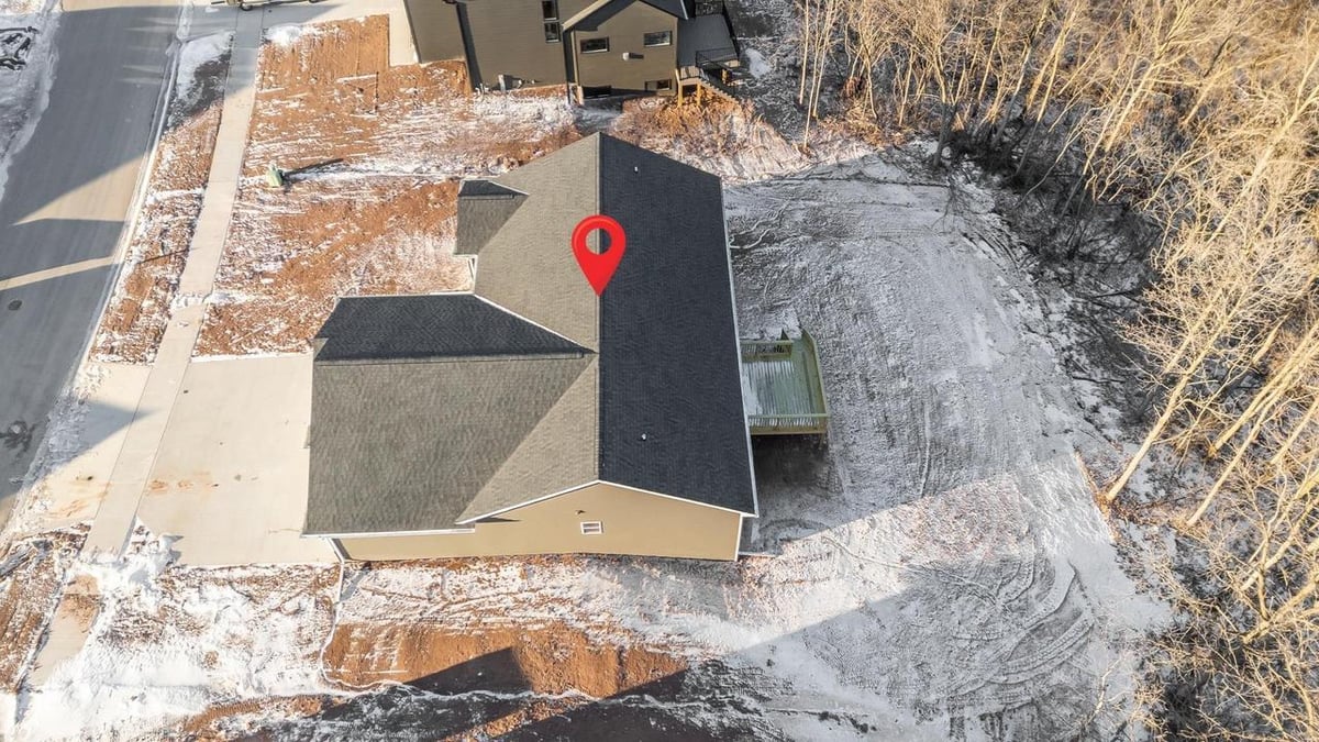 Aerial view of backyard and roof with location pin, wooded lot behind in a Fox Cities home