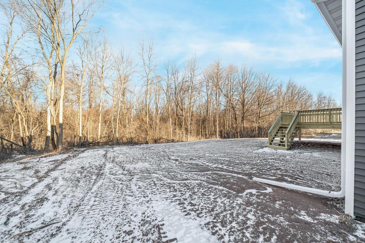 Backyard with light snow and deck stairs at a Fox Cities home