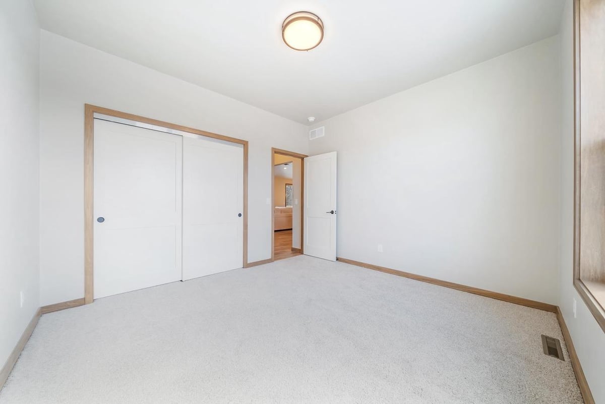 Bright bedroom with plush carpet and large window in the Fox Cities home
