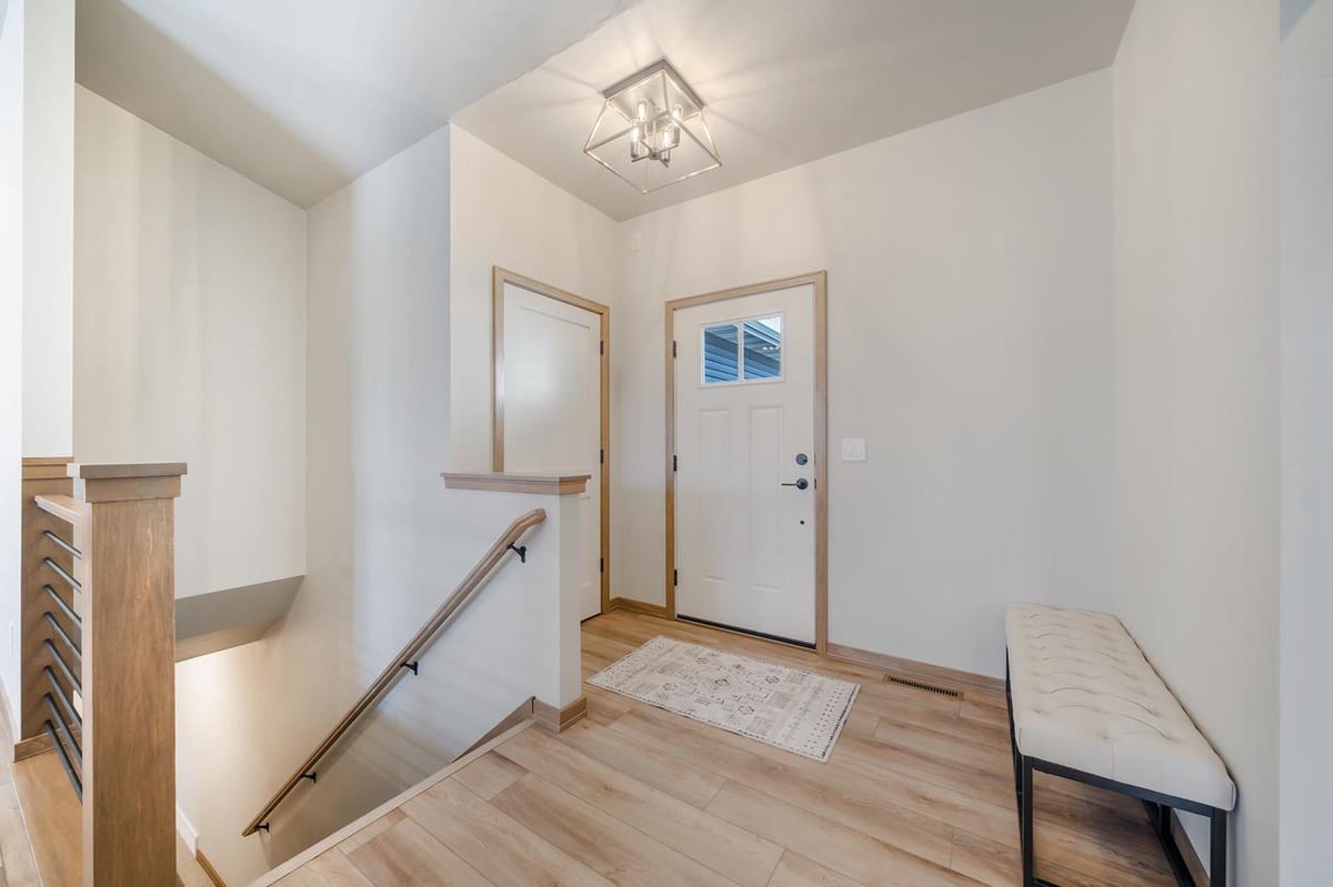 Entryway with staircase, bench seating, and modern light fixture in the Fox Cities