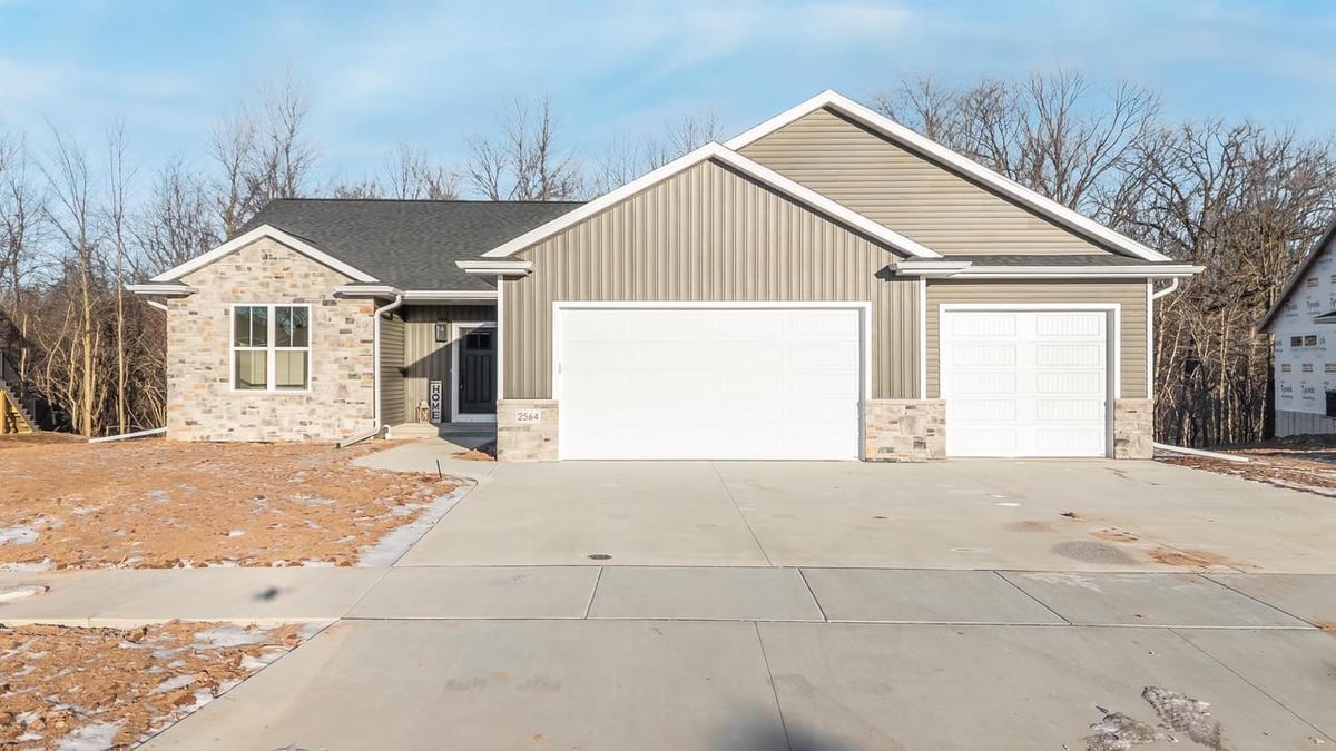 Exterior of a Fox Cities home with stone and siding facade, three car garage, and wide concrete driveway