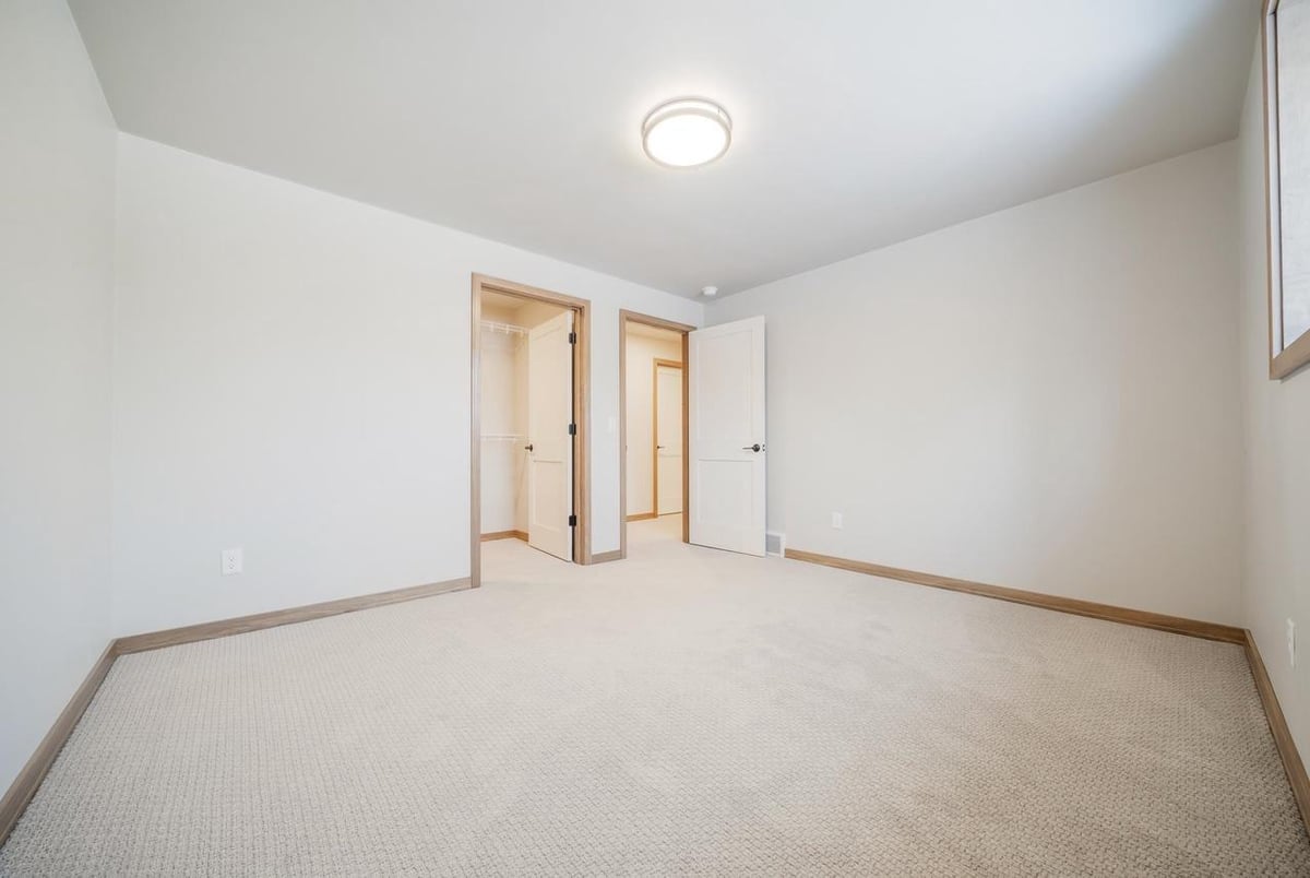 Fox Cities bedroom with double closets, neutral carpet, and simple modern finishes