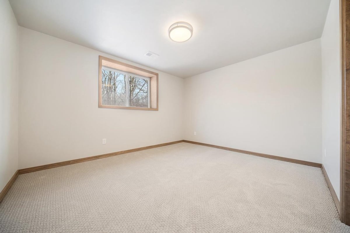 Fox Cities lower-level bedroom with neutral carpet and egress window