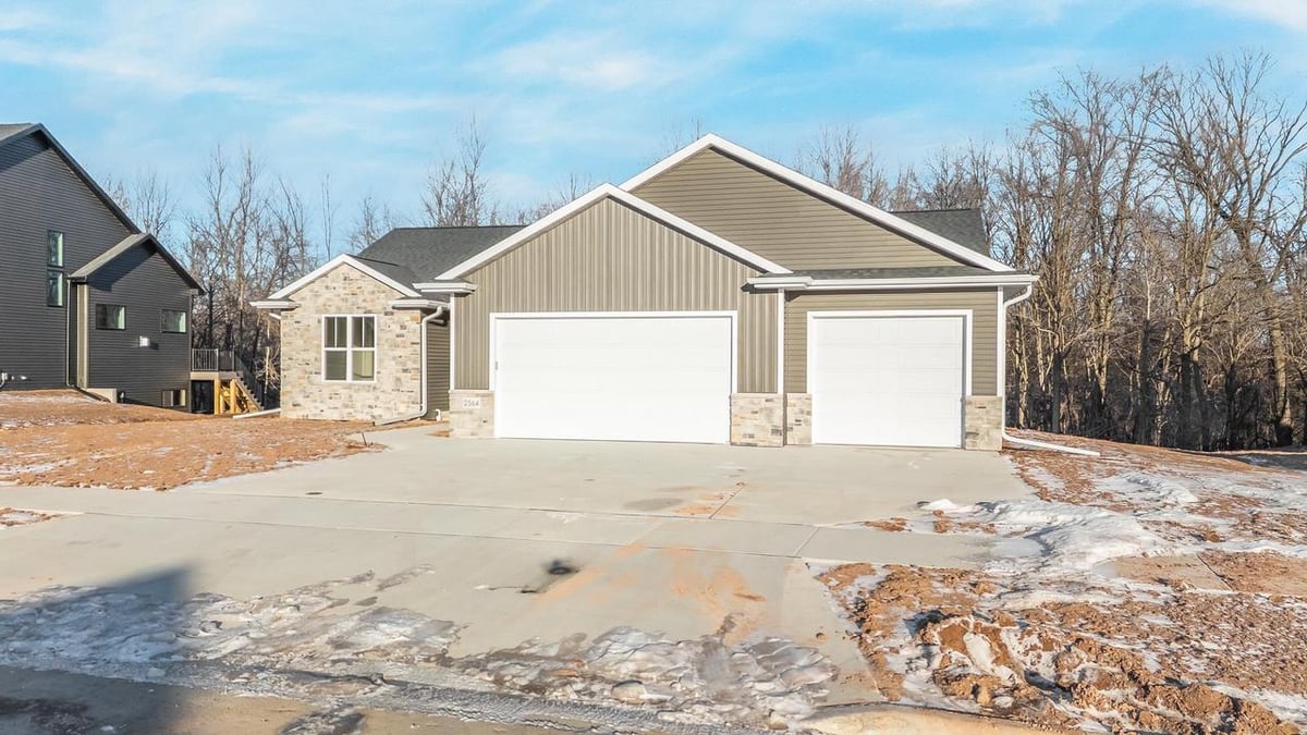 Front view of a Fox Cities home with attached garages, stone detail, and snow covered yard