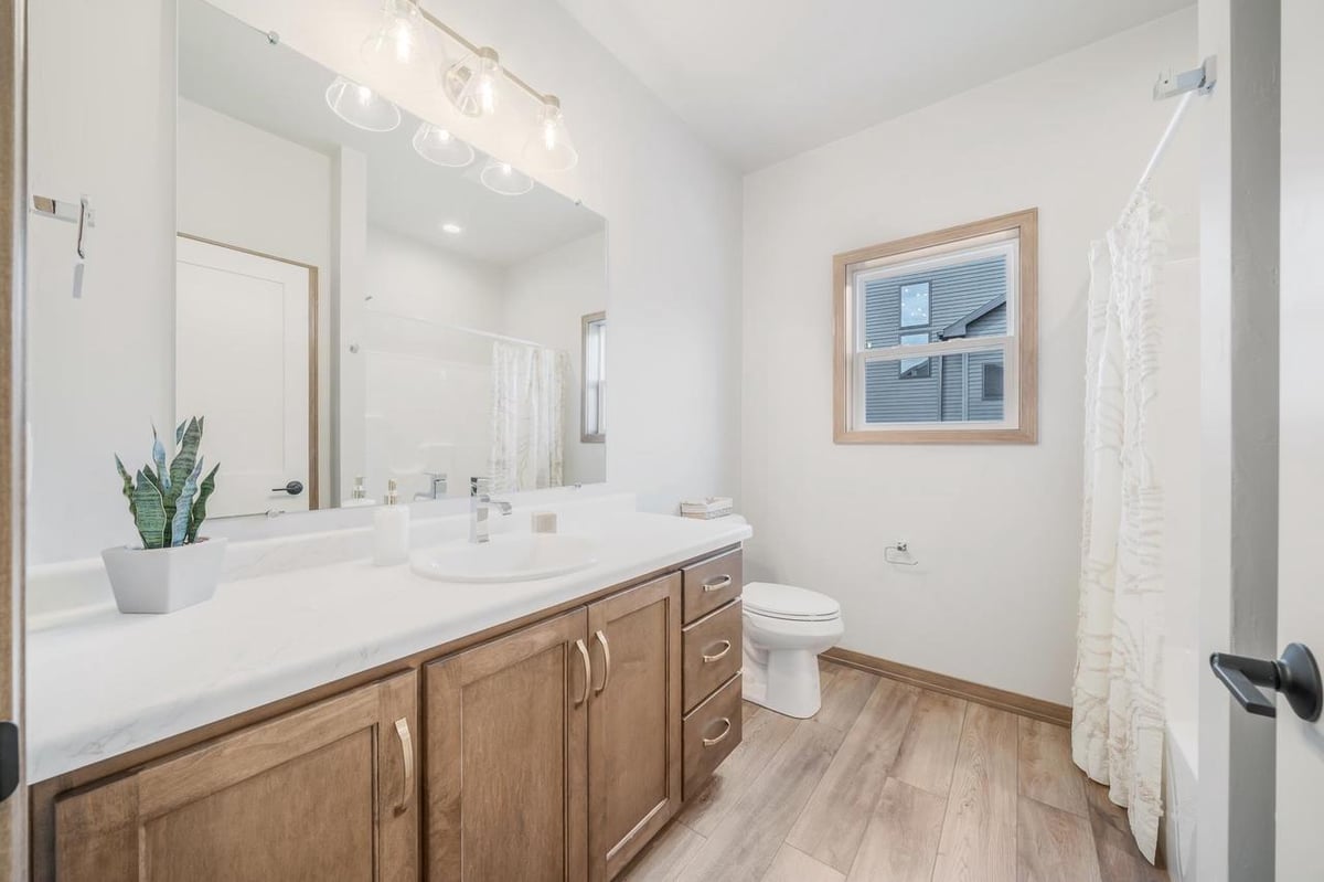 Full bath with wood vanity, large mirror, and tub shower in the Fox Cities