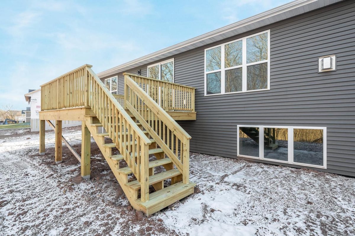 Snowy backyard with raised wood deck and stairs at a Fox Cities home