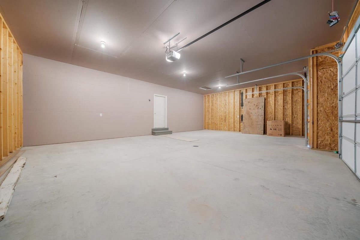 Spacious unfinished garage with drywall and overhead door in a Fox Cities home